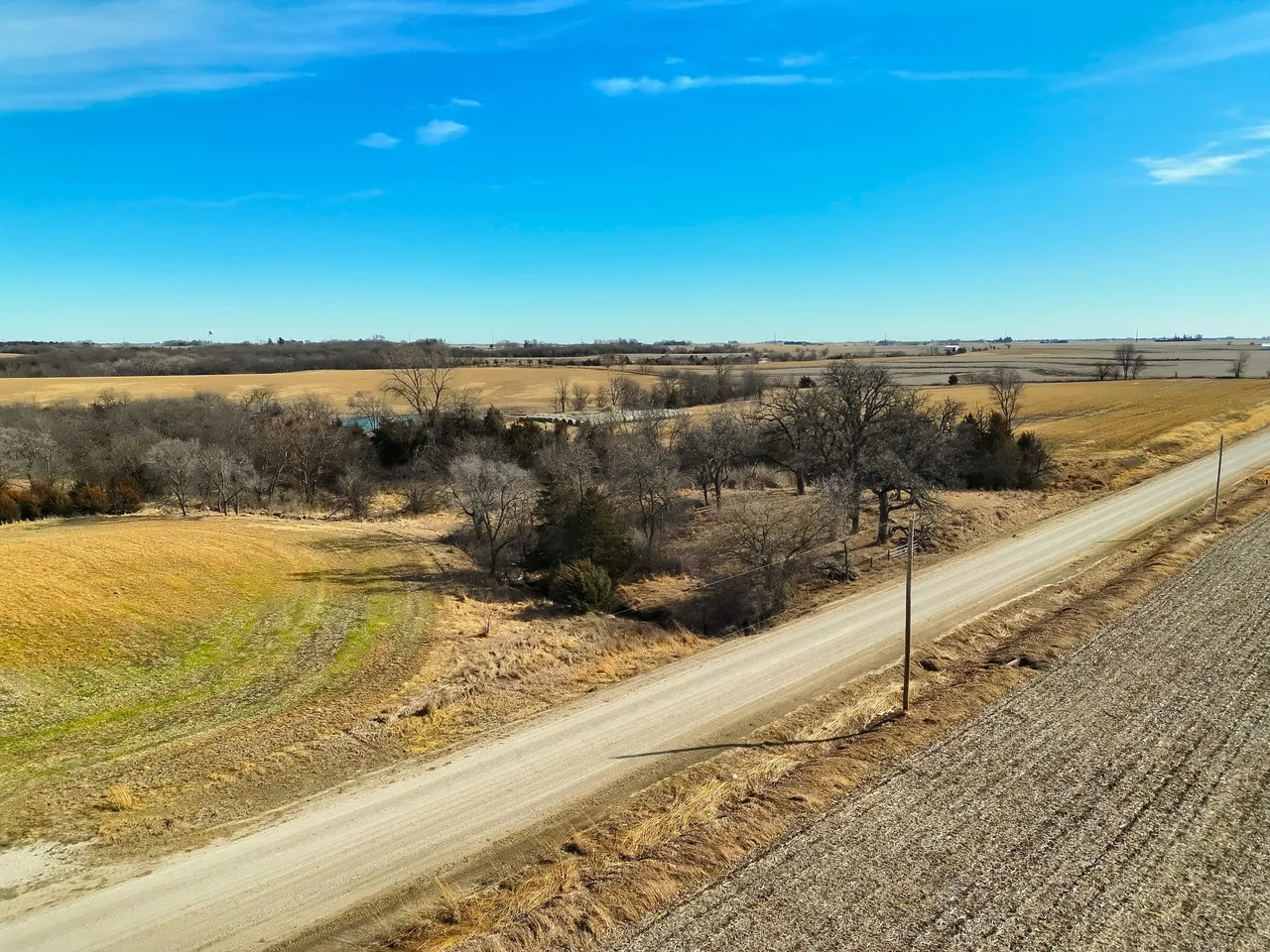 Rural dirt road through farmland under blue sky