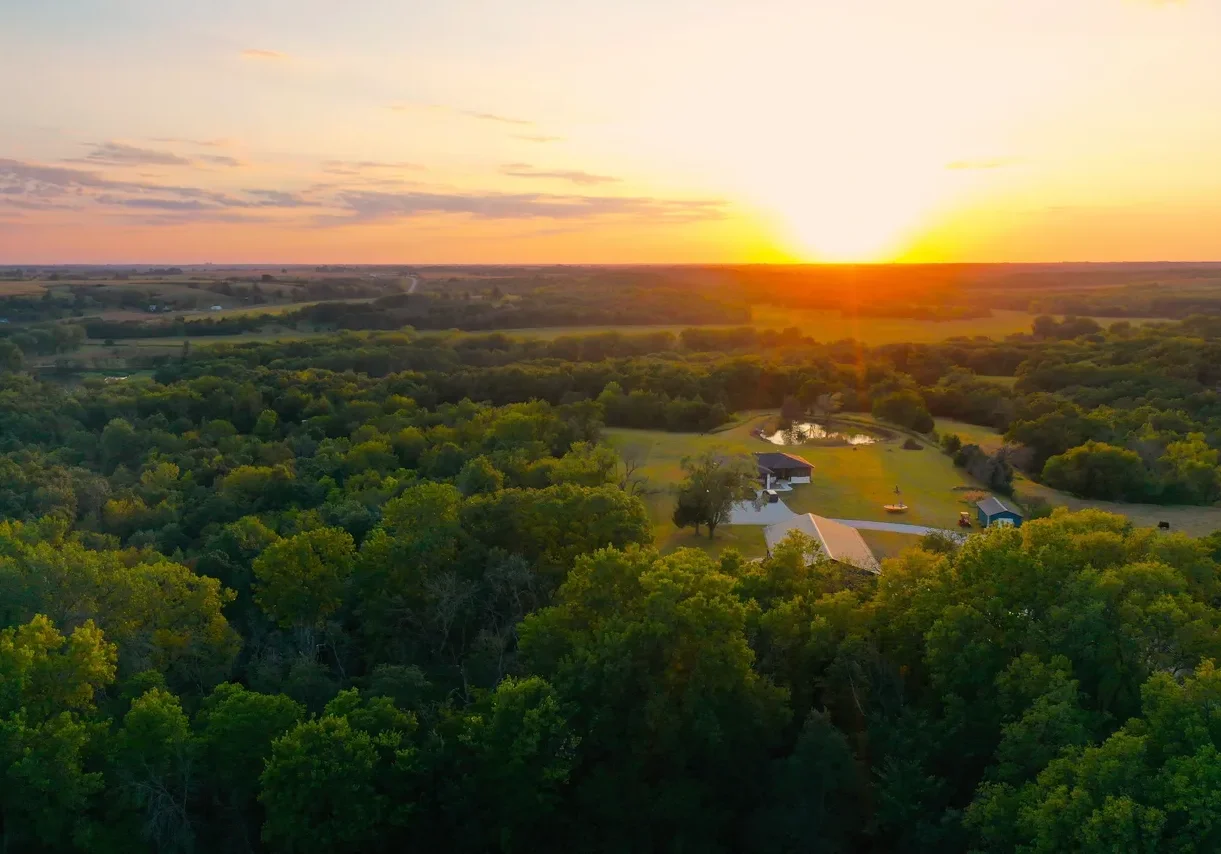 Aerial sunset over rural farmhouse and pond